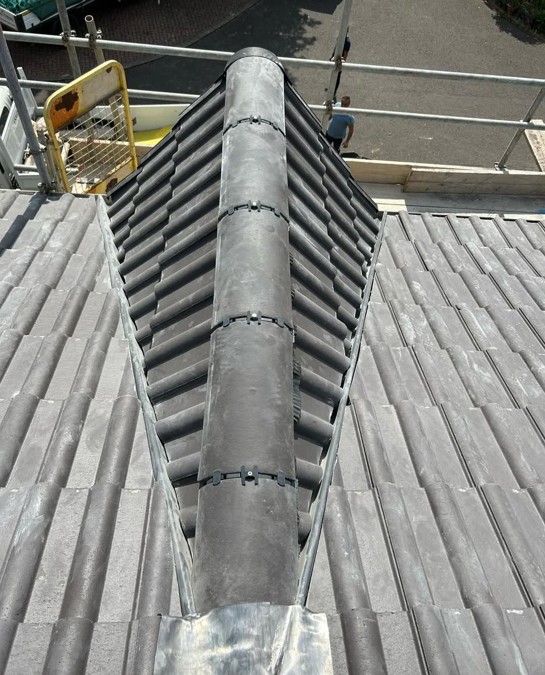 Newly fitted ridge tiles with dry ridge fixings on a tiled roof
